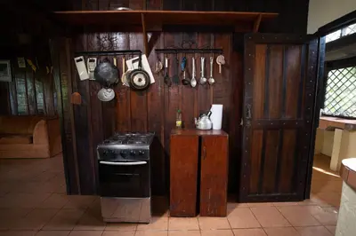 a kitchen with a stove and a wooden wall at Princesa de la Luna Ecolodge in Fortuna