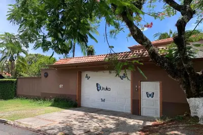 a house with two garage doors and a tree at Uruka Lodge in Alajuela City