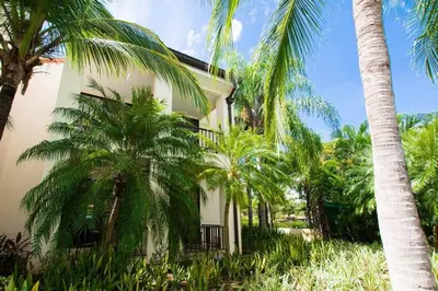a building with palm trees in front of it at Colorful 3-BD Unit Opening on Pool in Coco