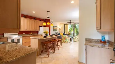 a kitchen with wooden cabinets and bar stools at 1-Bedroom Near Pool in Coco