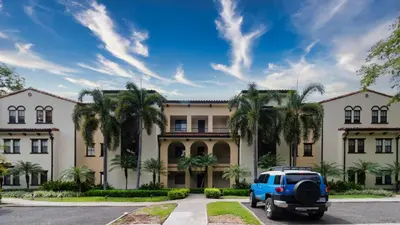 a blue suv parked in front of a large building at 1-Bedroom Near Pool in Coco