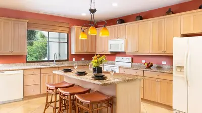 a kitchen with wooden cabinets and a island with bar stools at 1-Bedroom Near Pool in Coco
