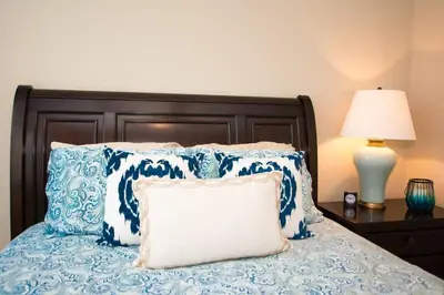 a bed with blue and white pillows and a lamp at Nicely Decorated 3rd-Floor Beauty with Pool-View Balcony in Coco in Coco