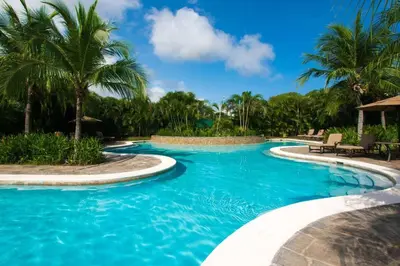 a swimming pool with blue water and palm trees at Nicely Decorated 3rd-Floor Beauty with Pool-View Balcony in Coco in Coco