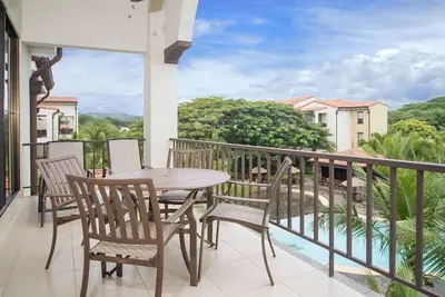 a patio with a table and chairs on a balcony at Impressively designed and decorated 3rd-floor space overlooking pool in Coco in Coco