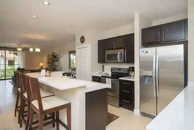 a kitchen with a stainless steel refrigerator and cabinets at Impressively designed and decorated 3rd-floor space overlooking pool in Coco in Coco