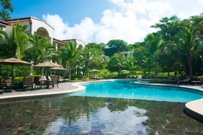 a pool at a resort with chairs and umbrellas at Chic Minimalist Condo with Swimming Pool, Hot Tub, and Beach Club Access in Coco