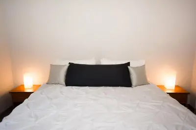 a white bed with two lights on two tables at Chic Minimalist Condo with Swimming Pool, Hot Tub, and Beach Club Access in Coco
