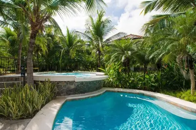 a swimming pool in a resort with palm trees at Chic Minimalist Condo with Swimming Pool, Hot Tub, and Beach Club Access in Coco