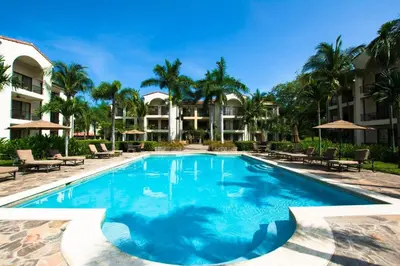 a swimming pool at a resort with palm trees at Chic Minimalist Condo with Swimming Pool, Hot Tub, and Beach Club Access in Coco