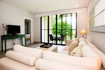 a living room with a white couch and a television at Chic Minimalist Condo with Swimming Pool, Hot Tub, and Beach Club Access in Coco
