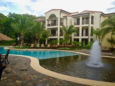 a swimming pool with a fountain in front of a building at Third-Floor Oceanview Condo with Access to Sparkling Pool, Hot Tub & Beach Club in Coco
