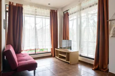 a living room with a chair and a tv and windows at Mundaka : Burnt Toast Surfcamp in Nosara