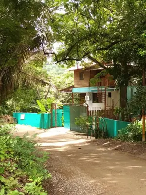 a house with a blue fence next to a road at Mundaka : Burnt Toast Surfcamp in Nosara