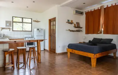 a bedroom with a bed and a kitchen with a counter at Mundaka : Burnt Toast Surfcamp in Nosara