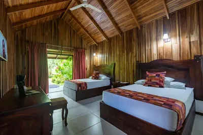 a bedroom with two beds and a desk and a window at Hotel Volcan Verde in Fortuna