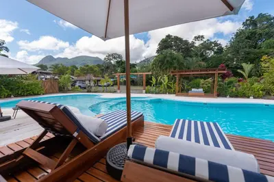a swimming pool with two lounge chairs and an umbrella at Hotel Volcan Verde in Fortuna