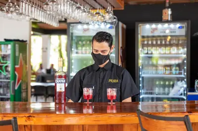 a man in a mask standing at a bar with a drink at Hotel Volcan Verde in Fortuna