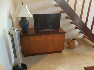 a television on a wooden stand next to a staircase at Casa Claudia in Potrero