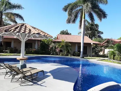 a pool with two chairs and a umbrella and palm trees at Casa Claudia in Potrero