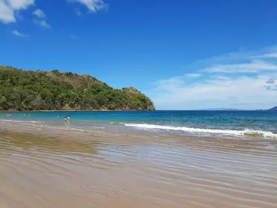a beach with a group of people in the water at Casa Claudia in Potrero
