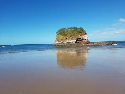 a rock in the water on a beach at Casa Claudia in Potrero