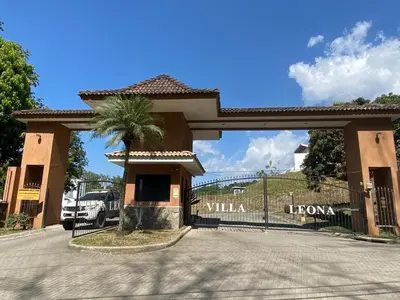 a entrance to a villa with a palm tree and a fence at Punta Leona Beach Condos in Jacó