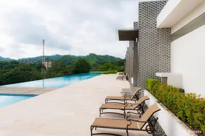 a row of chairs sitting on the edge of a swimming pool at Luxury Beach Apartment Herradura Fishermen And Family in Herradura