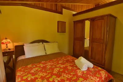 a bedroom with a bed with a red comforter at Mirador House Cozy & Private Home W Volcano View in El Castillo de la Fortuna