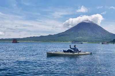 a man in a raft on a lake with a mountain at Mirador House Cozy & Private Home W Volcano View in El Castillo de la Fortuna