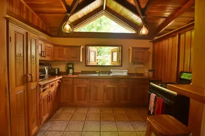 a kitchen with wooden cabinets and a large window at Mirador House Cozy & Private Home W Volcano View in El Castillo de la Fortuna