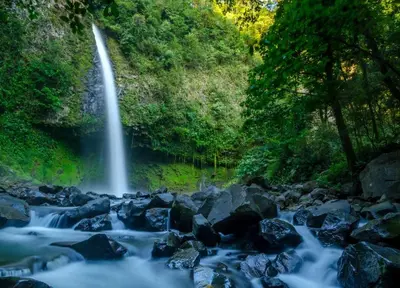 a waterfall in the middle of a river with rocks at Pie In The Sky 2 Luxury Home With Amazing Views! in El Castillo de La Fortuna