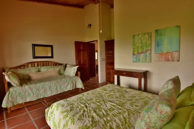 a bedroom with a bed and a bed and a table at Pie In The Sky 3 Stunning Lake & Volcano Views! in El Castillo de La Fortuna