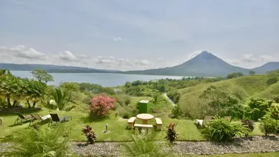 a garden with a table and chairs and a view of a mountain at Pie In The Sky 3 Stunning Lake & Volcano Views! in El Castillo de La Fortuna