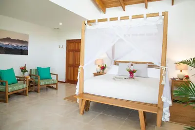 a bedroom with a canopy bed and two chairs at Tierra Magnifica Boutique Hotel in Nosara