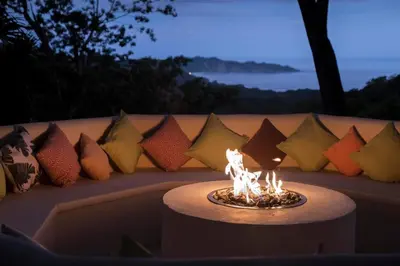 a fire pit in front of a couch with pillows at Tierra Magnifica Boutique Hotel in Nosara