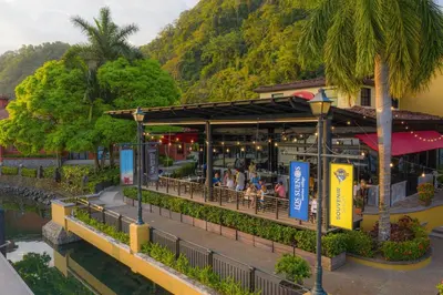 a restaurant with people sitting outside of it next to a river at Bella Vista 2B 3 bdrs pool view in Los Suenos in Herradura