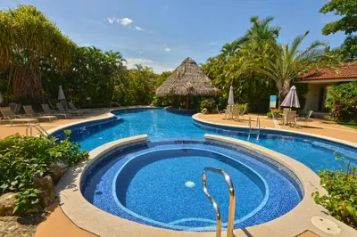 a pool at a resort with chairs and a table at Colina 9E 2 bdr Garden View in Los Suenos in Herradura