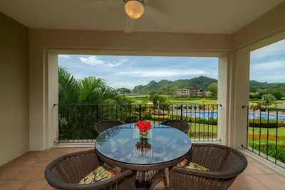 a glass table with a vase of flowers on a balcony at Del Mar 3i 3 bdr Ocean View in Los Suenos in Herradura