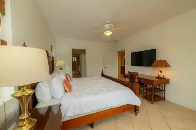 a bedroom with a bed and a desk and a television at Del Mar 4G 3 bdr Garden View in Los Suenos in Herradura