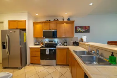 a kitchen with wooden cabinets and a stainless steel refrigerator at Del Mar 4O 2 bdr Garden View in Los Suenos in Herradura