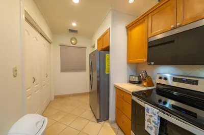 a kitchen with a stainless steel refrigerator and wooden cabinets at Del Mar 4O 2 bdr Garden View in Los Suenos in Herradura