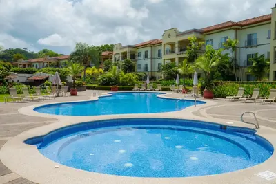a pool at a resort with chairs and condos at Del Mar 4O 2 bdr Garden View in Los Suenos in Herradura