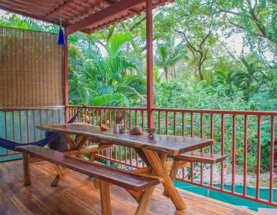 a wooden table and bench on a wooden deck at J Bay : Burnt Toast Surfcamp in Nosara