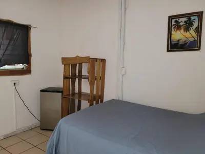 a bedroom with a bed and a wooden chair at J Bay : Burnt Toast Surfcamp in Nosara