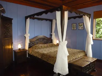 a bedroom with a four poster bed with curtains at Arco Iris Lodge in Monteverde Costa Rica
