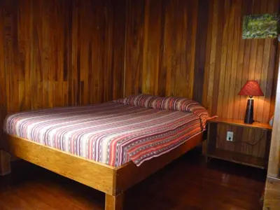a bedroom with a bed and a lamp on a table at Arco Iris Lodge in Monteverde Costa Rica