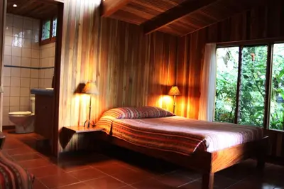 a bedroom with a bed with two lamps and a window at Arco Iris Lodge in Monteverde Costa Rica