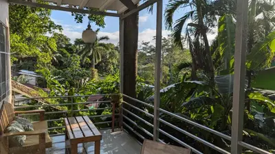 a porch with a bench and a view of the jungle at Peace of Paradise Breakfast Included Free Manuel Antonio Park Tour in Manuel Antonio