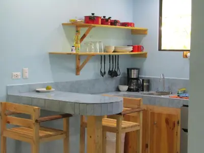 a kitchen with a counter with chairs and a table at Peace of Paradise Breakfast Included Free Manuel Antonio Park Tour in Manuel Antonio